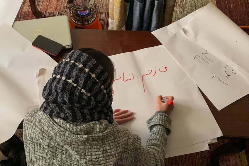 Una mujer afgana escribe pancartas contra las prohiciones impuestas por los talibanes a las mujeres