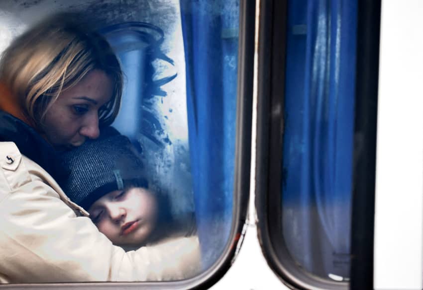 Una mujer y su hijo son vistos a través de la ventana de un autobús mientras llegan a un centro de alojamiento temporal tras huir de la invasión rusa de Ucrania, en Korczowa, Polonia