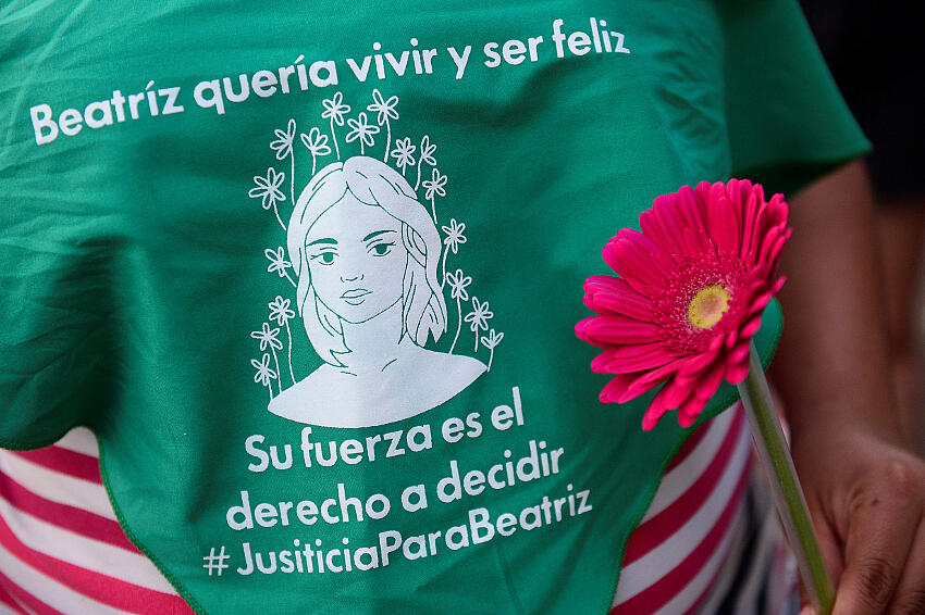 Una mujer sostiene una flor cerca de un pañuelo verde en memoria de Beatriz, una mujer salvadoreña que murió después de que la Corte Suprema de El Salvador le negara un aborto médico