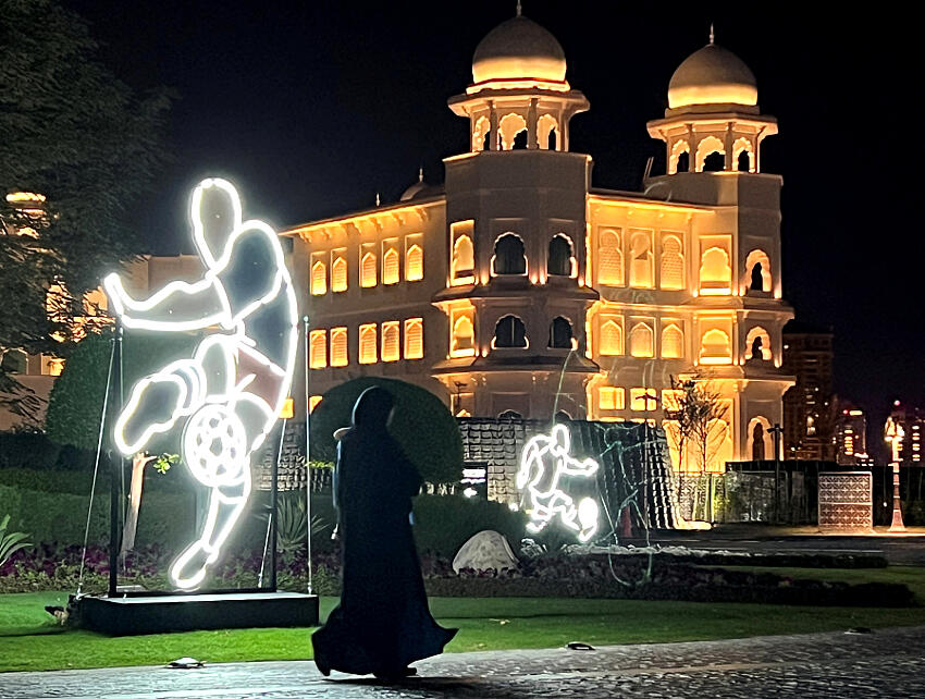 Una mujer pasa junto a una instalación artística iluminada que promociona la Copa Mundial de la FIFA 2022 en Doha, Qatar, un país que viola los derechos de las mujeres