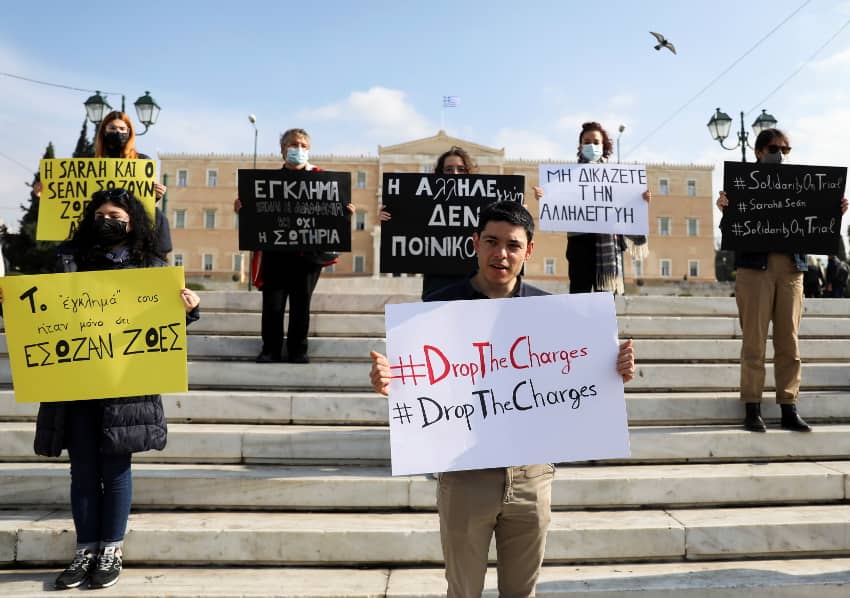 Sean Binder sostiene una pancarta que pone "drop the charges" (retiren los cargos) durante una manifestación de activistas de Amnistía Internacional en solidaridad con Sarah Mardini y con él