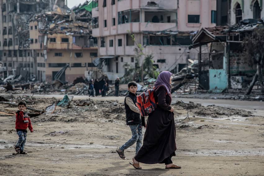 Una madre palestina camina con sus hijos entre los escombros en Gaza
