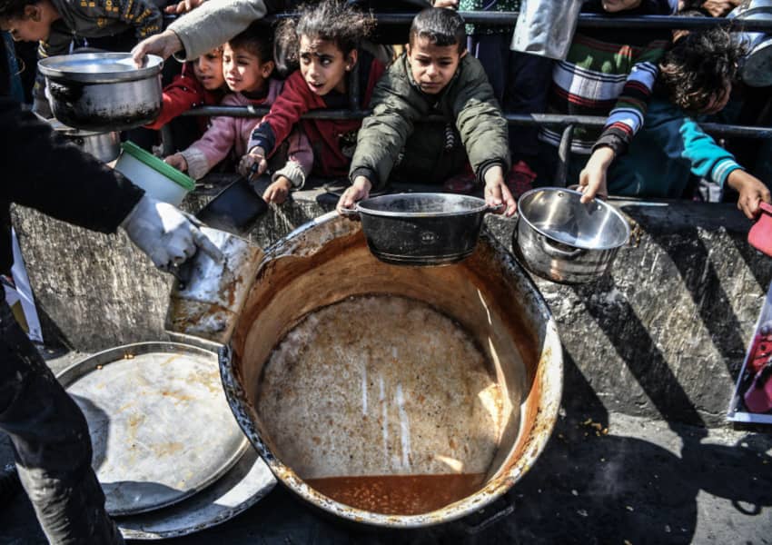 Menores sostienen sus platos para que se los llenen de alimentos