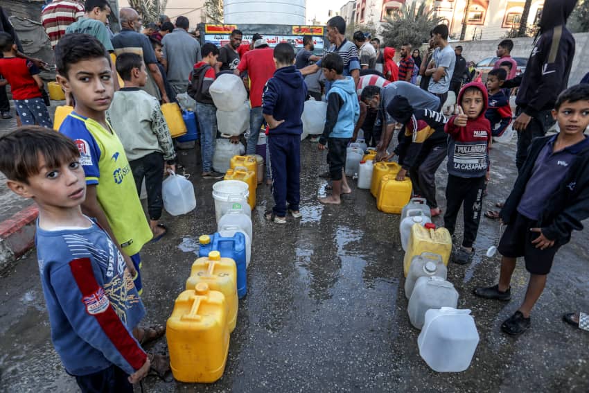 Varios menores hacen cola para llenar sus bidones de agua