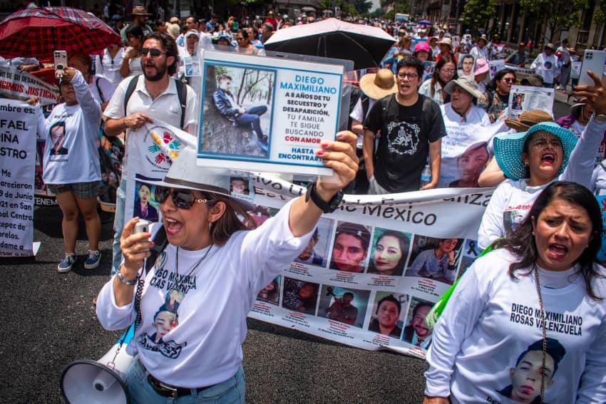 Mujer levanta la imagen de una persona desaparecida en una marcha de madres buscadoras en la Ciudad de México