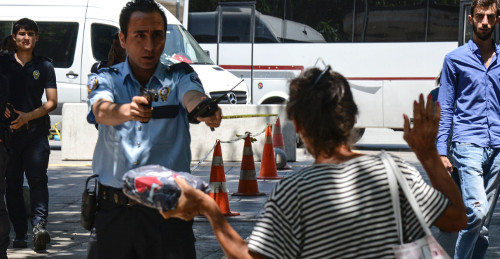 Un policía turco apunta con su arma a una mujer, pidiéndole que deje el paquete que está llevando, frente del palacio de justicia. © ILYAS...