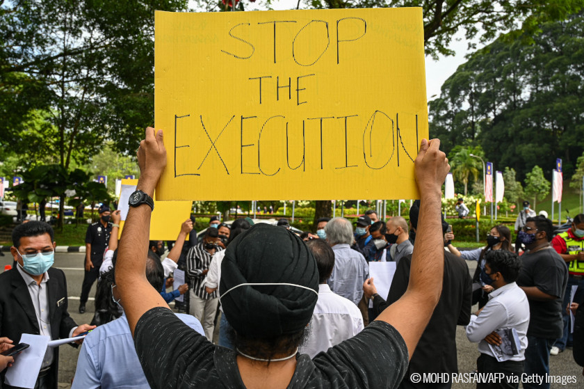 Manifestante con un cartel que dice paren la ejecución