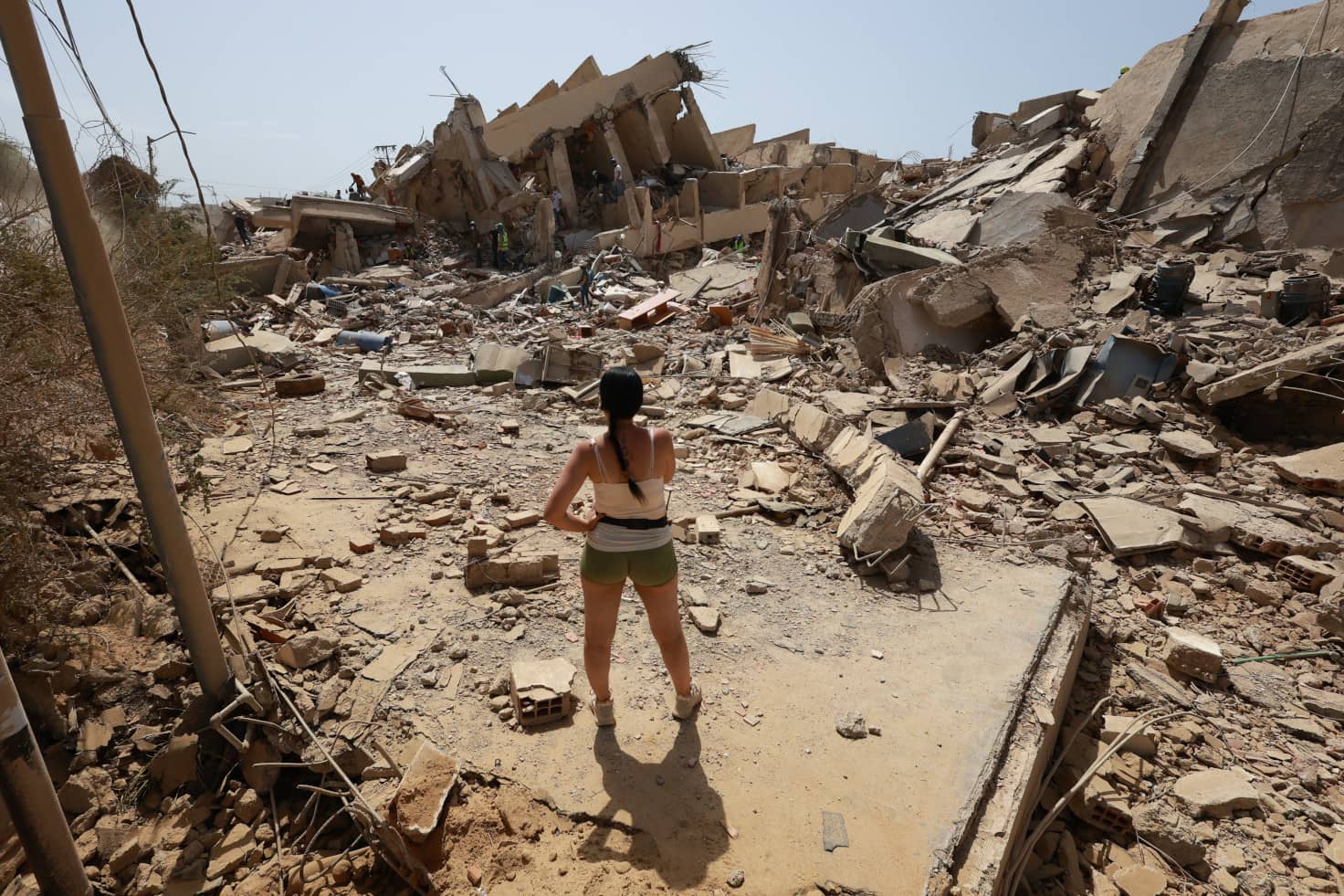 Dos días después de los devastadores terremotos, una joven permanece de pie frente a los escombros de las casas derrumbadas.