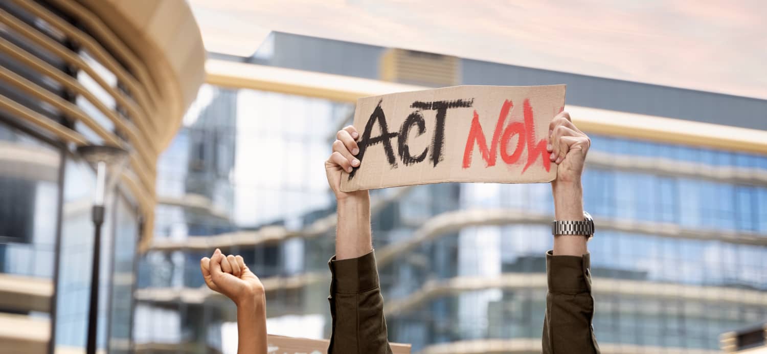 Un activista sostiene un cartel que pone "Actúa ahora"